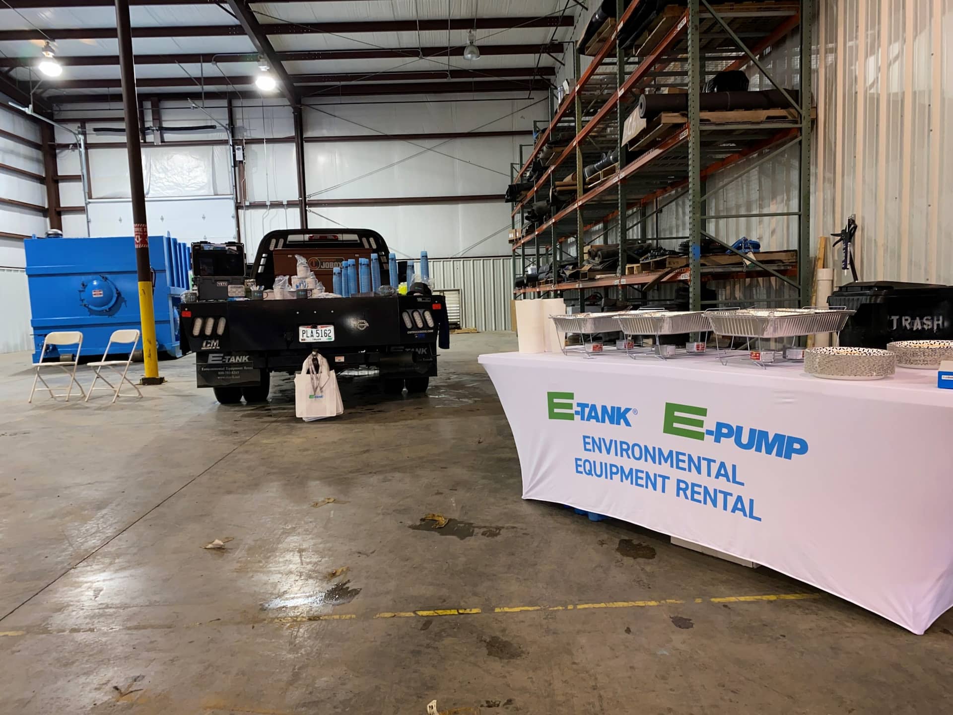 E-Tank and E-Pump environmental equipment rental open house setup with display tables, frac tank, and service truck inside facility