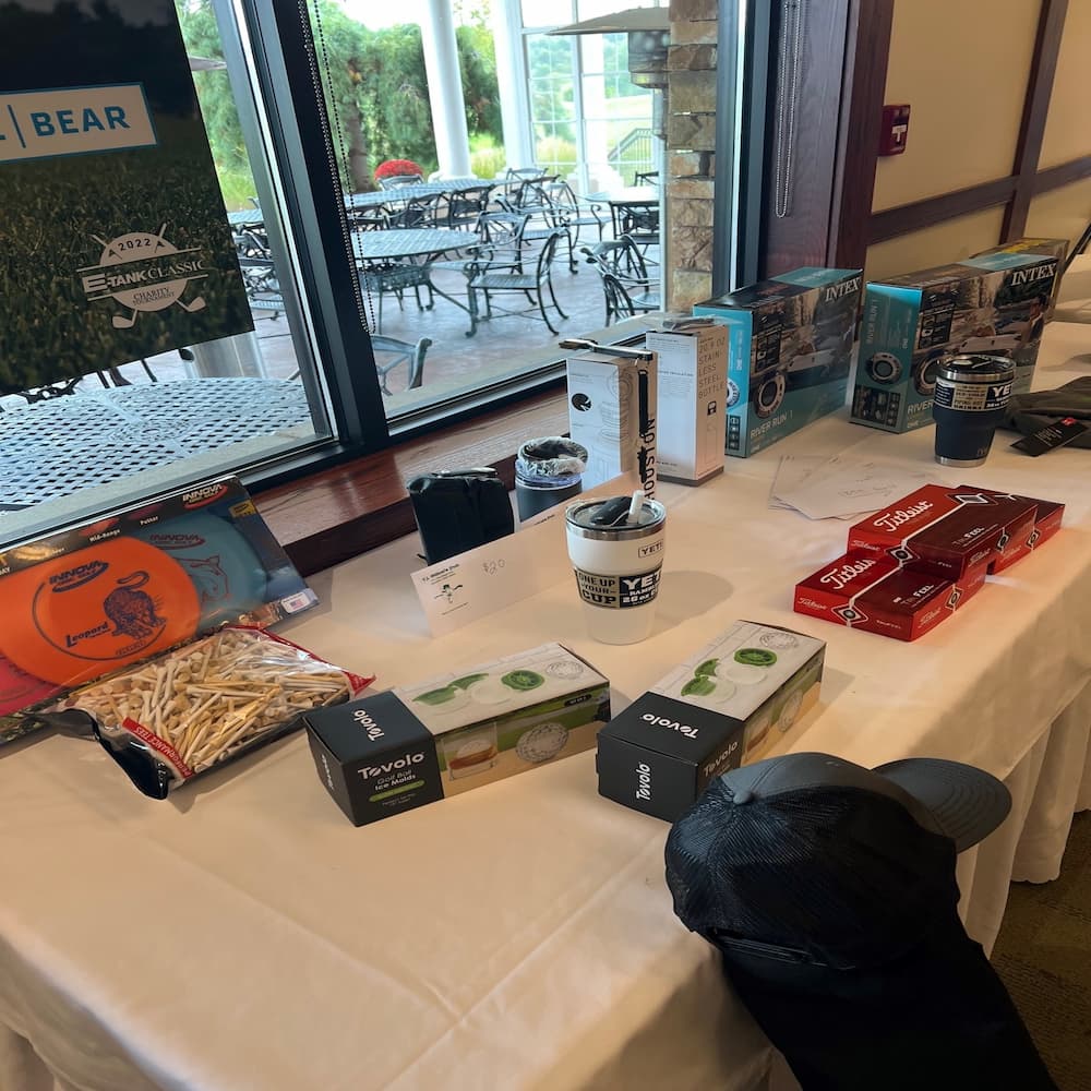 Close-up of raffle prizes including Intex float sets, Yeti tumblers, and Titleist golf balls displayed at the E-Tank Classic golf fundraiser.