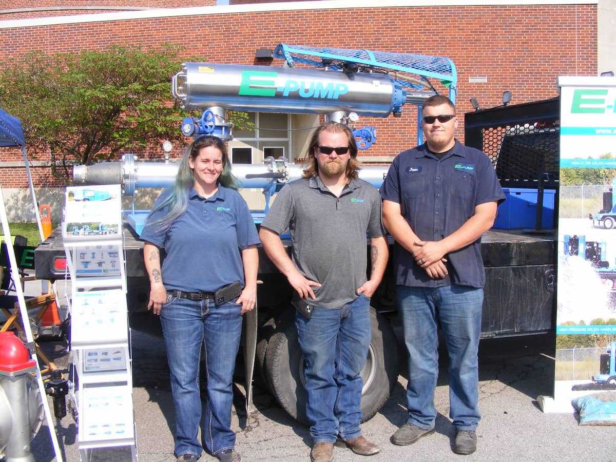 E-Pump team members standing in front of pump equipment during community demonstration event, representing E-Tank services and expertise