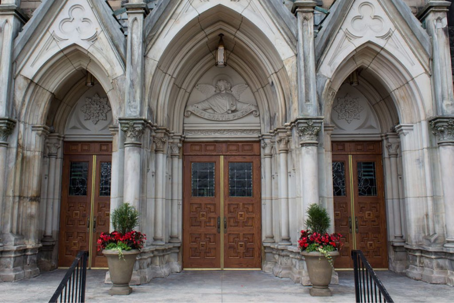 Custom wood church doors with decorative glass and historical Gothic arch detailing at St. Mary’s Catholic Church in Akron, Ohio, by Rockwood Door & Millwork.
