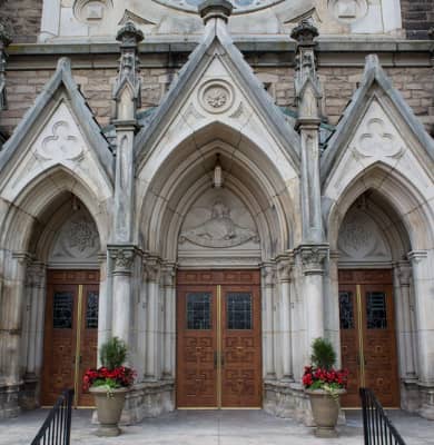 Custom reproduction wood doors with decorative glass panels at St. Mary’s Catholic Church in Akron, Ohio, handcrafted by Rockwood Door & Millwork to match the building’s historic Gothic architecture.