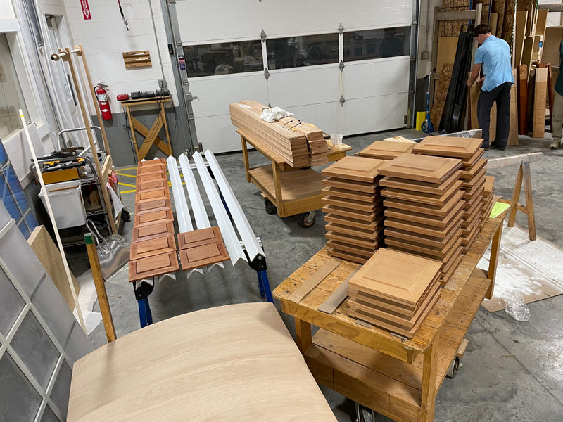Stacks of custom-crafted wood door panels and parts inside Rockwood Door & Millwork’s shop, showing detailed joinery and preparation for a historic school renovation.