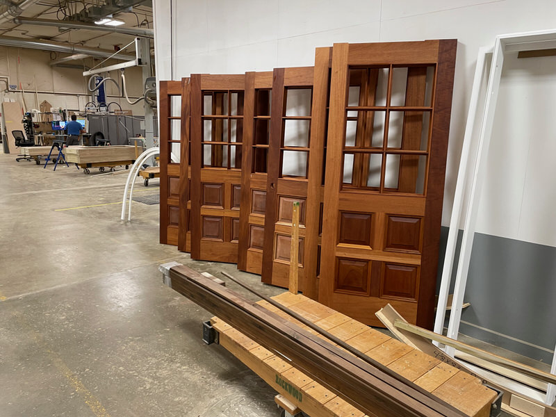 Custom White Oak and Mahogany entry doors with glass lites and raised panels, fabricated by Rockwood Door & Millwork for the Metro at Indianola historic school renovation project.