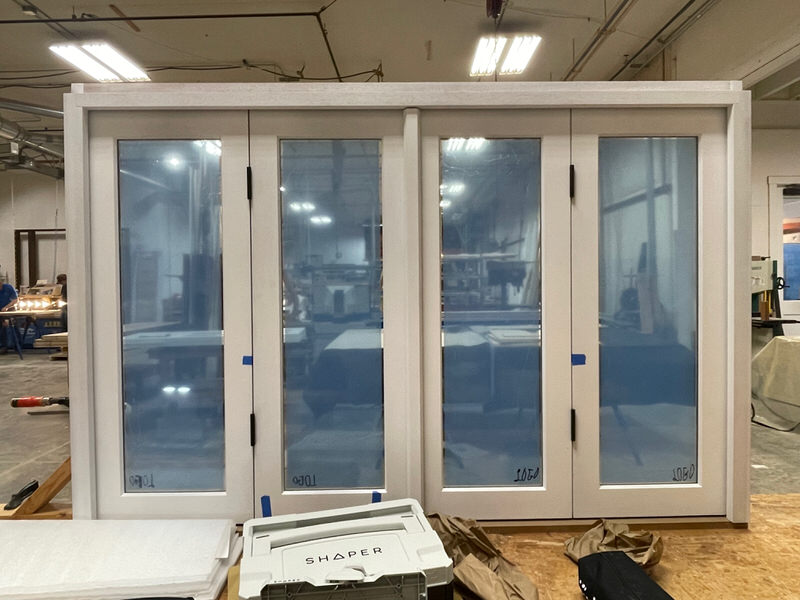 Completed four-panel pass-through window with protective blue film, painted finish, and concealed folding hardware—built for exterior pool house use.