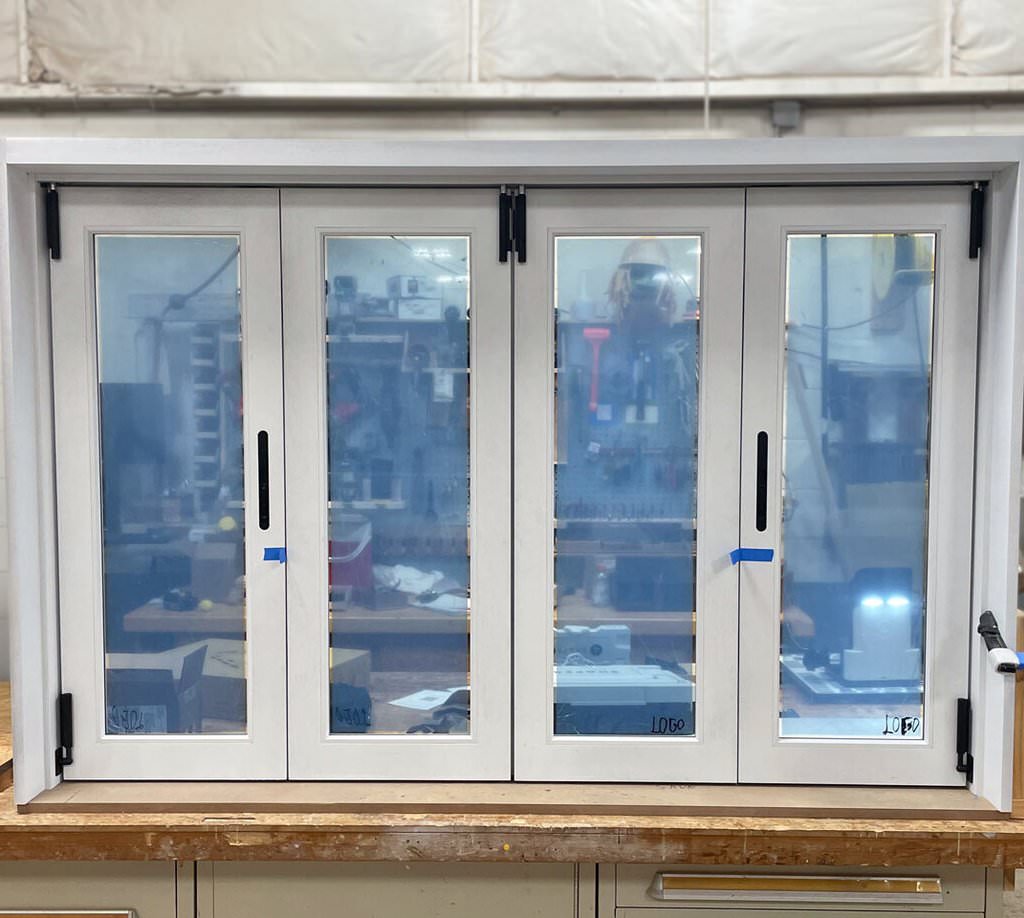 Final installed pass-through pool house window with clean white finish and folding glass panels, designed by Rockwood.