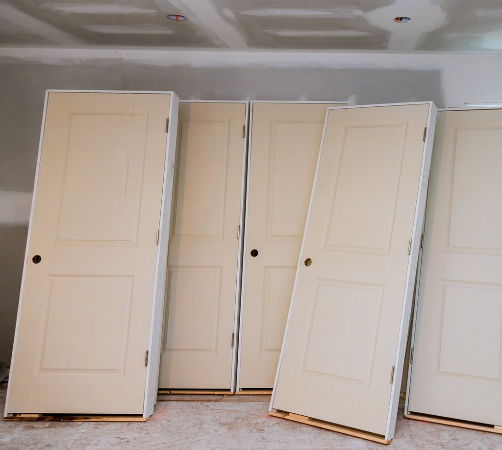 Off-the-shelf standard interior doors leaning against a wall in a construction setting—highlighting the difference between mass-produced doors and the custom craftsmanship offered by Rockwood Door & Millwork.