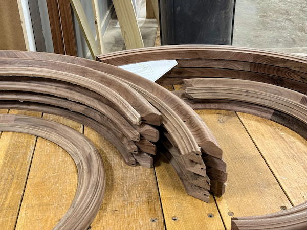 Curved walnut millwork components in fabrication at Rockwood, prepared for custom arched interior doors in a South Dakota mountain-modern home.