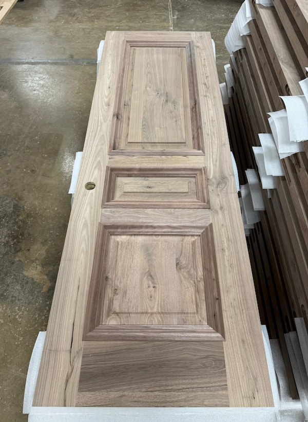 Finished rustic walnut interior door by Rockwood, featuring deep moulded panels and fine grain detail for a South Dakota mountain-modern home.