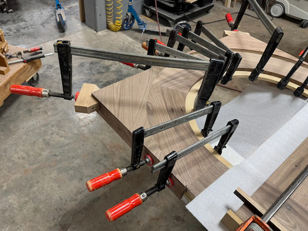 Walnut arch components clamped during glue-up at Rockwood’s workshop, part of the custom door and millwork fabrication process.