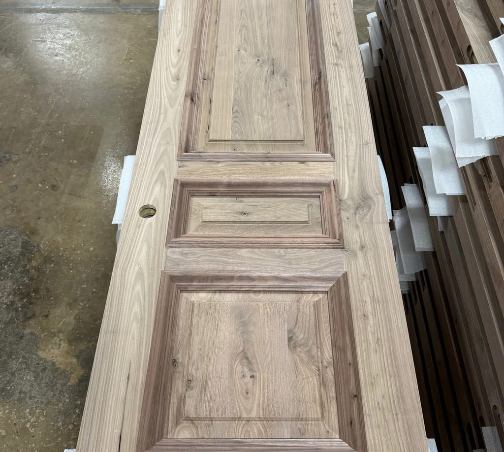 Rustic walnut interior door in production at Rockwood Door & Millwork, showing handcrafted panel details for a South Dakota mountain-modern residence.